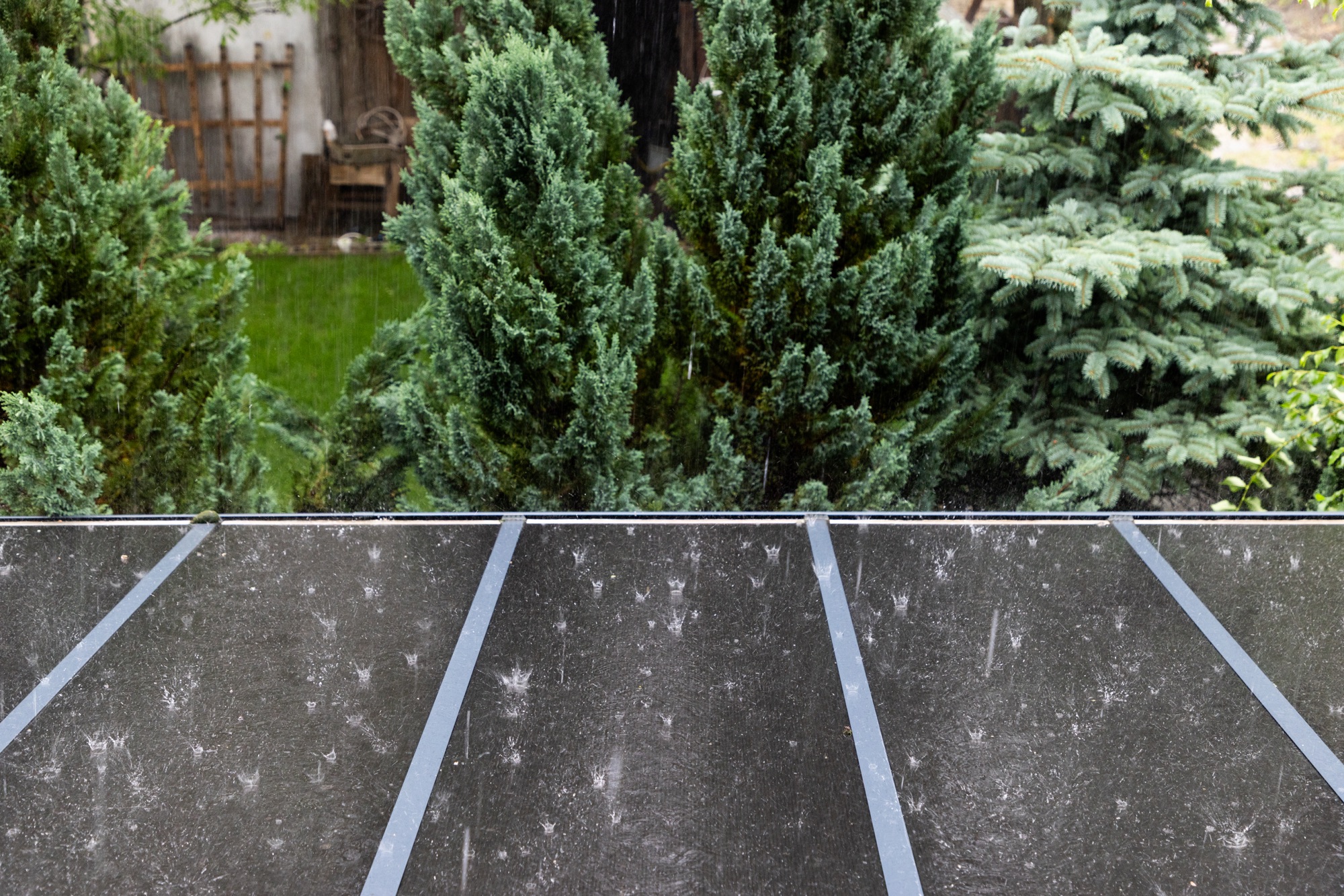 Regen prasselt laut auf eine Terrassenüberdachung aus Polycarbonat
